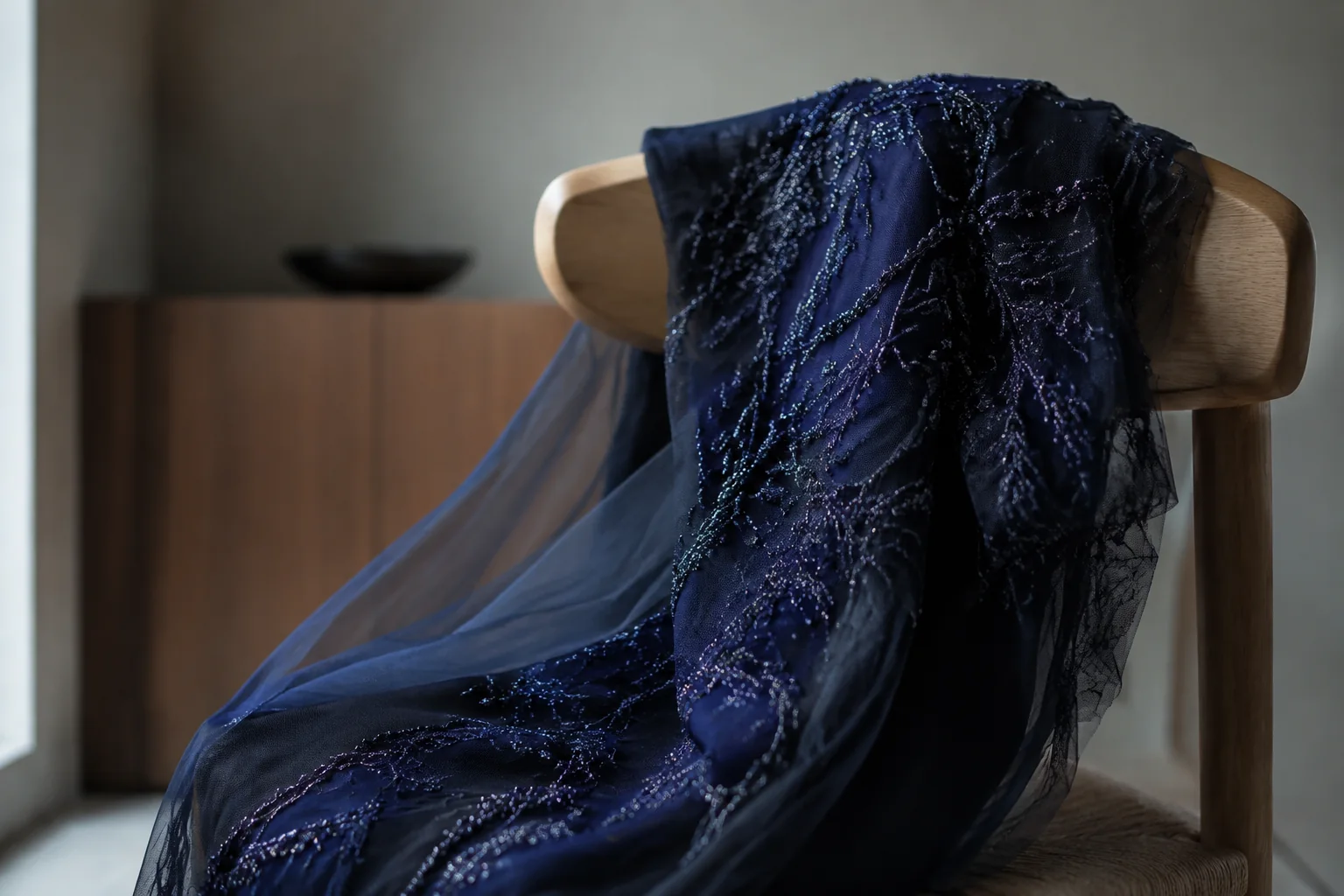 AI editorial concept: midnight-blue beaded fabric draped over a simple pale wooden chair.